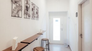 Um corredor com uma mesa comprida, dois banquinhos e obras de arte fixadas na parede.