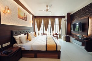 Una habitación de hotel moderna con una cama grande, televisión, escritorio y ventilador de techo.