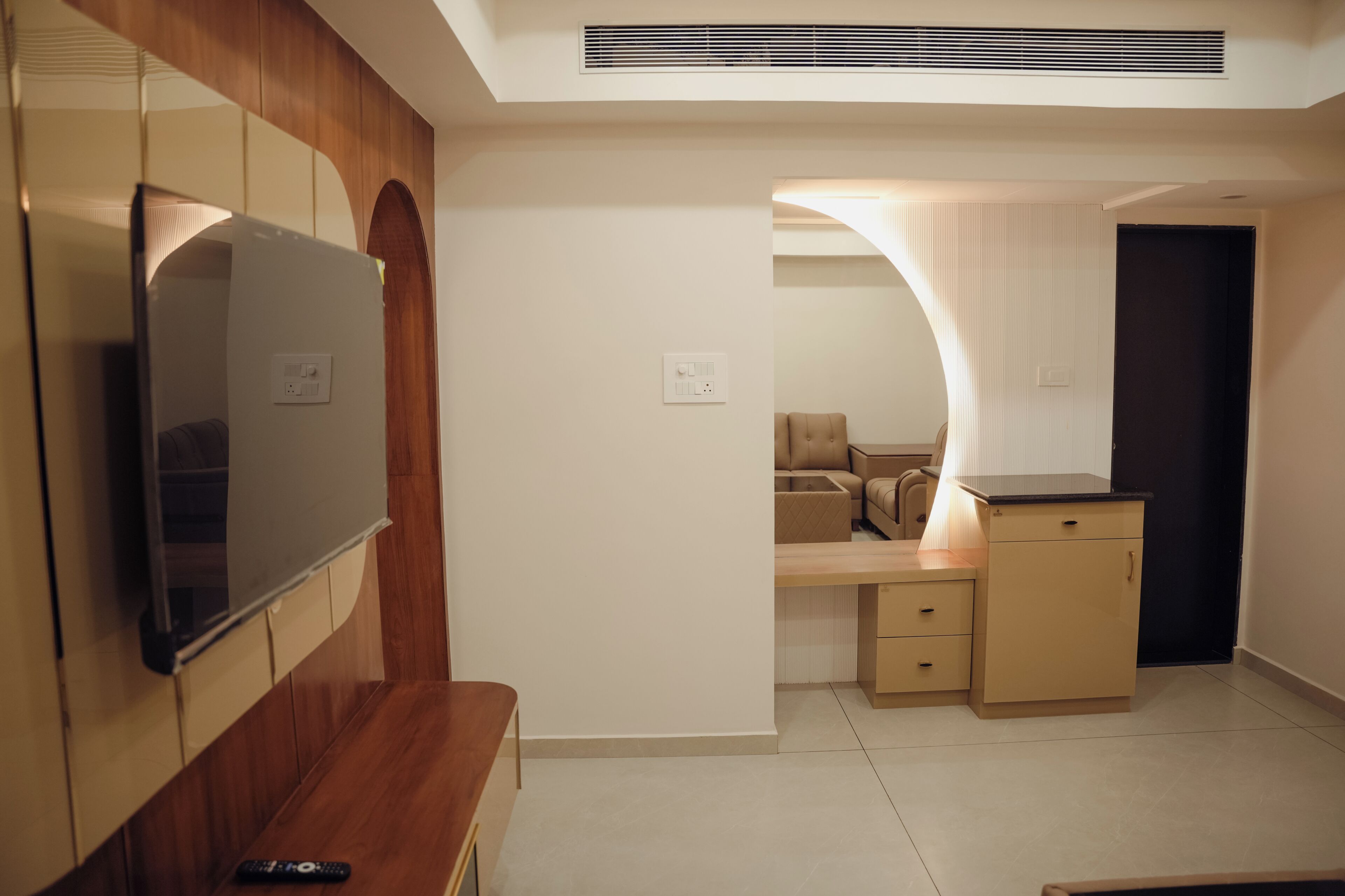 Una habitación moderna con televisión, paneles de madera, un banco, un escritorio y una silla.