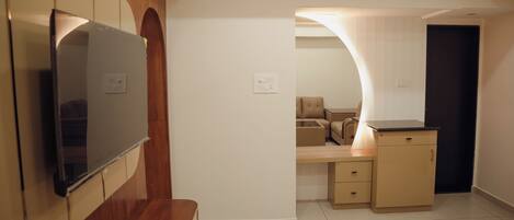 Una habitación moderna con televisión, paneles de madera, un banco, un escritorio y una silla.