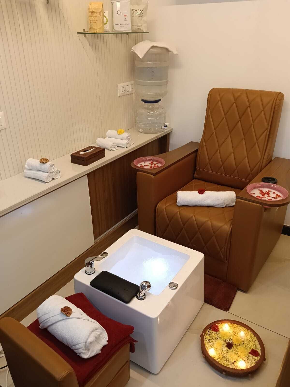 A spa room with a massage chair, a foot bath, and a small table with towels and a water dispenser.