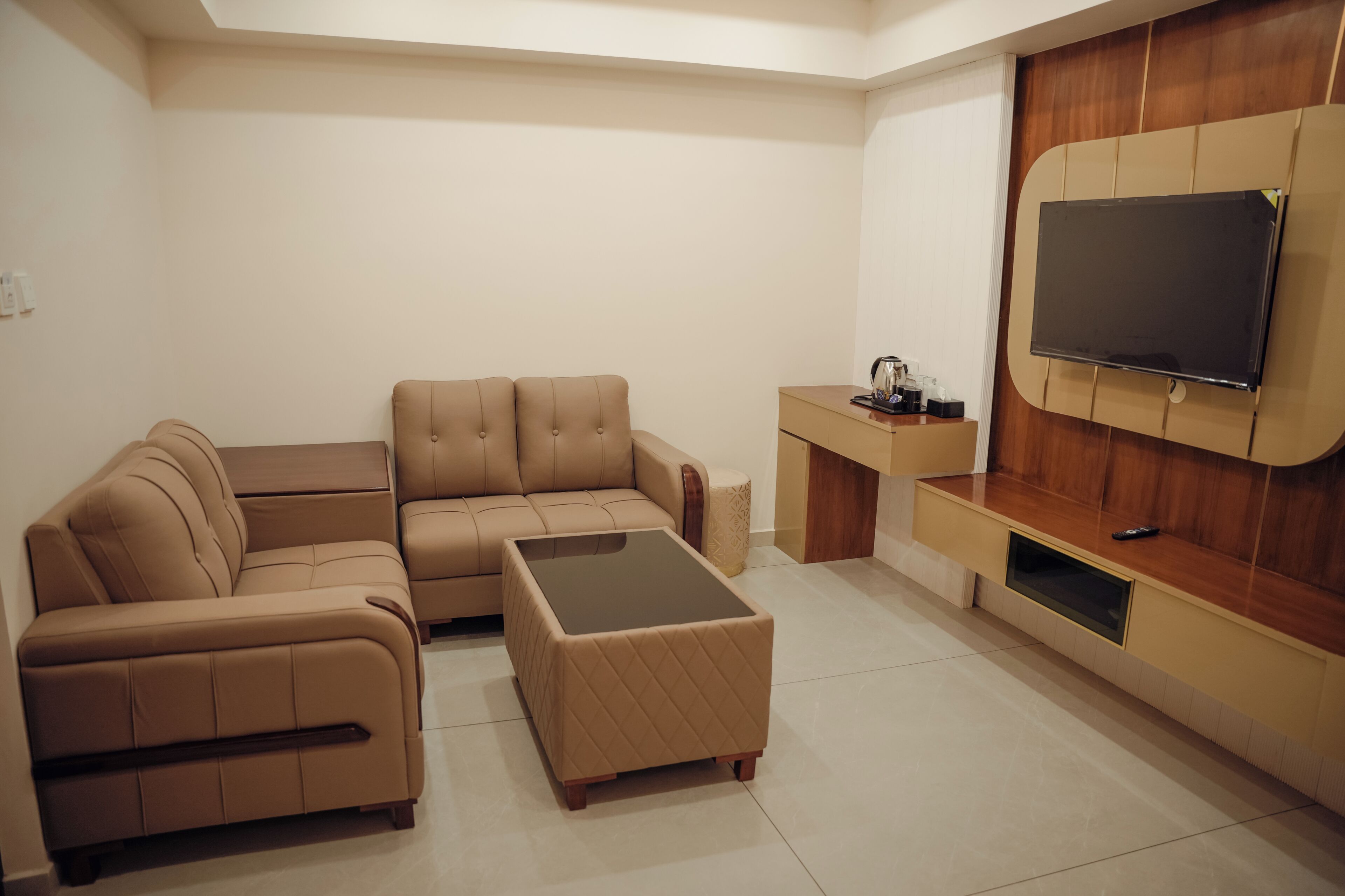 Una sala de estar moderna con un sofá seccional, una mesa de centro, un televisor montado en una pared de madera y una mesita auxiliar.