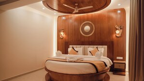 Ein rundes Bett mit Holz-Kopfstück, einem Deckenventilator und Wandleuchten.