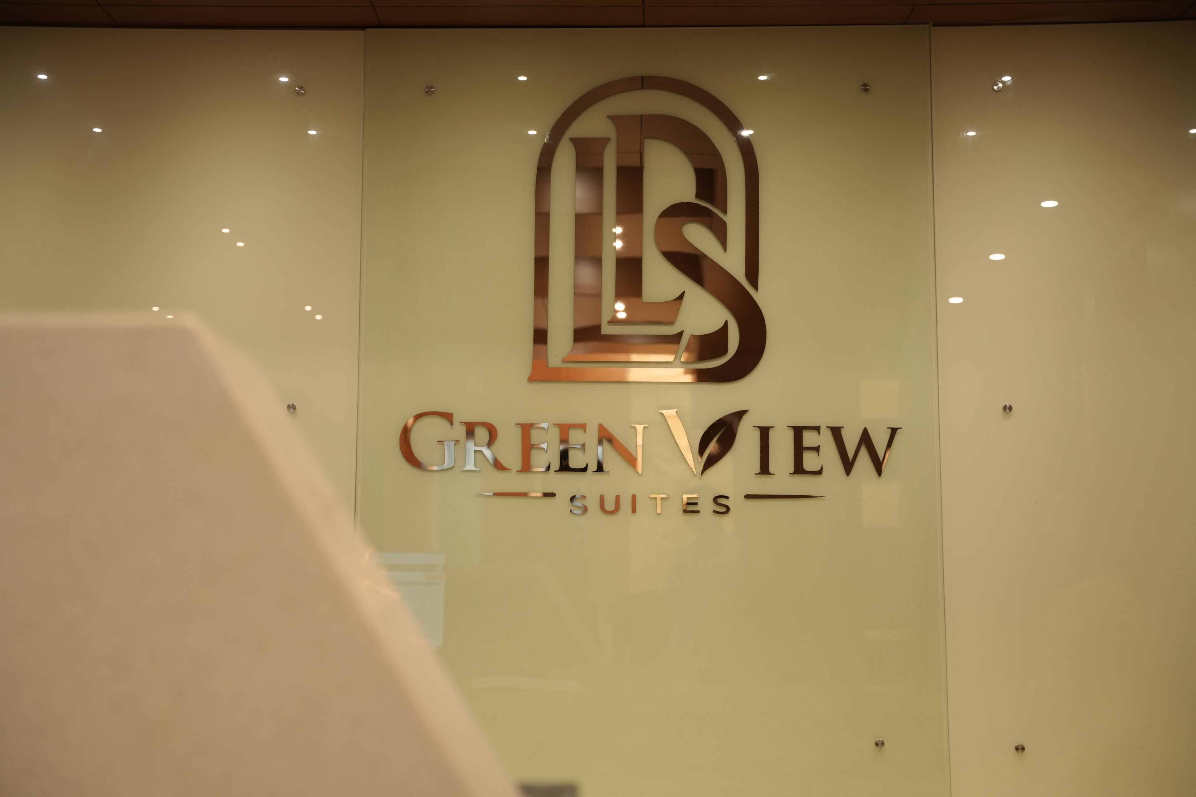 Un letrero de hotel con el nombre 'Green View Suites' y un logotipo estilizado.
