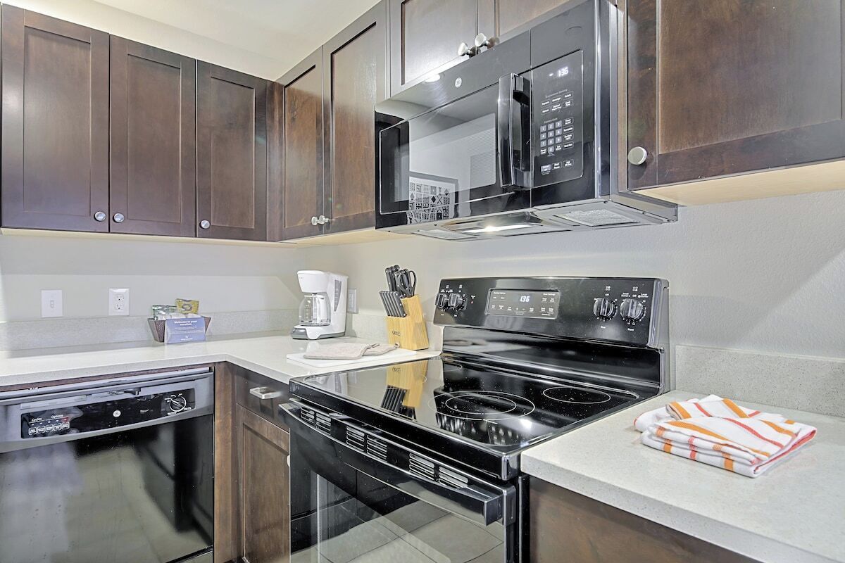 A modern kitchen with dark wooden cabinets, a black stove, and a microwave.