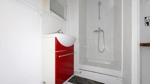 A bathroom with a white sink, red cabinet, and a shower with a glass door. - Studio Charmant Paris 15eme Proche Metro (Paris)