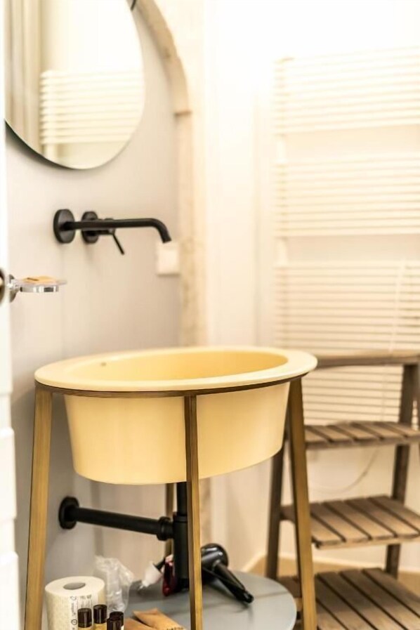A bathroom with a round yellow sink, a mirror, a towel rack, and a toilet paper holder. - DOMUS SAN GIOVANNI (Locorotondo)