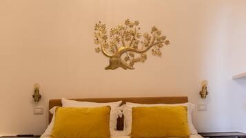 Ein Bett mit weißer und gelber Bettwäsche, ein an der Wand befestigter Baumschmuck und Nachttischlampen.