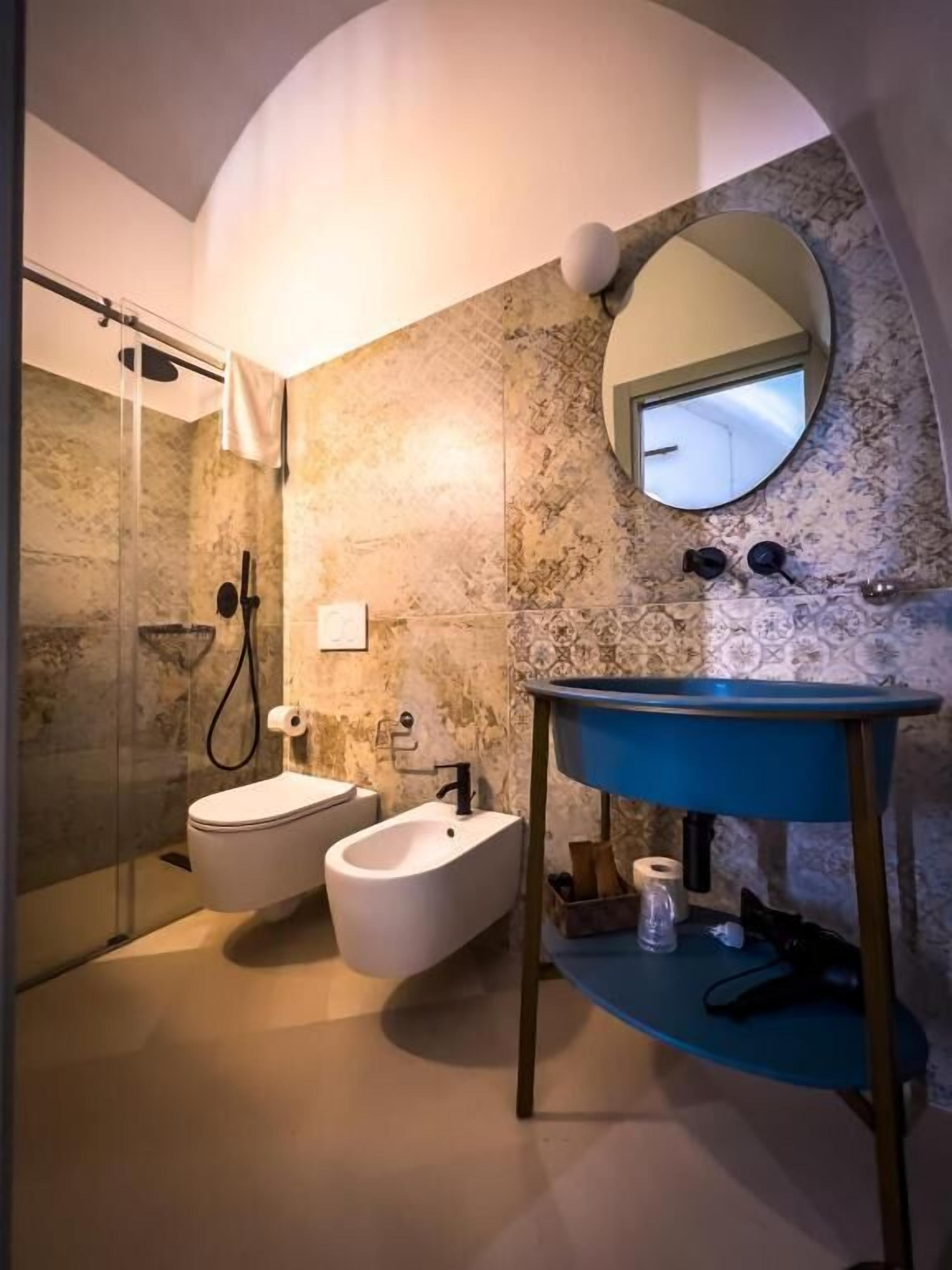 Een moderne badkamer met een douche, twee wastafels, een spiegel en een blauwe wastafelmeubel.