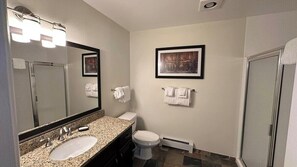 Une salle de bain équipée d’un lavabo, de toilettes, d’une douche et d’œuvres d’art encadrées accrochées au mur.