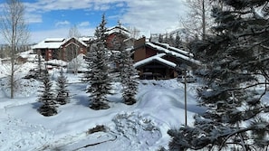 A snow-covered resort with multiple buildings, including a lodge with a sloped roof and a parking area. - Two 2-Bedroom Condos w/Fireplace, Hot Tub & Sauna (Steamboat Springs)
