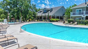 Ein Pool mit Liegestühlen, einem überdachten Bereich und einem Gebäude mit einem Giebeldach.