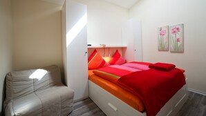 Een slaapkamer met een bed, een stoel en kunst aan de muur.