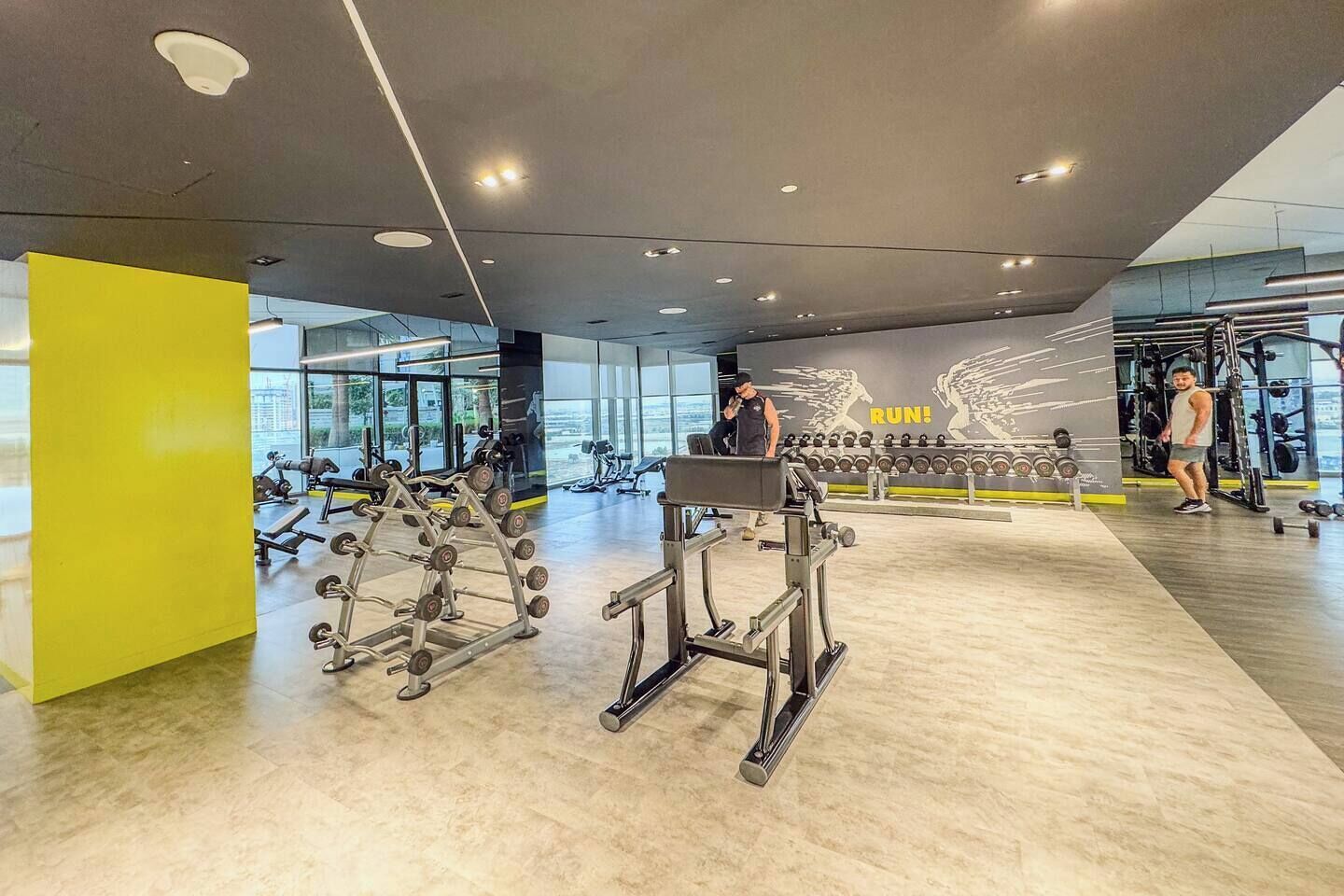 Ein modernes Fitnessstudio mit Krafttrainingsgeräten, Cardiogeräten und einer motivierenden Wand.