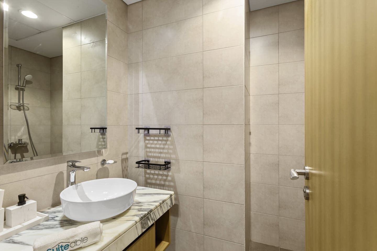 Une salle de bain moderne avec un grand miroir, un lavabo et une douche.