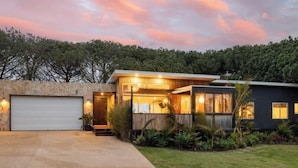 A modern house with a garage, a covered porch, and a well-maintained lawn. - The tropical farm rural acre with a tropical feel sprawling views 5 mins to town (Ventnor)