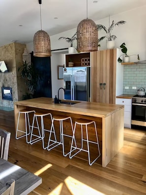 A modern kitchen with a central island, pendant lights, and wooden cabinetry.