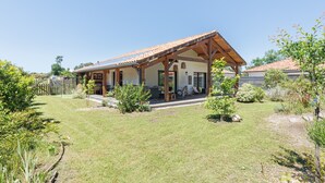 Ein Haus mit überdachter Terrasse, Rasen und Garten.