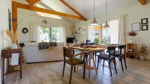 Eine geräumige Küche mit Holzbalken, einem Essbereich mit Stühlen, einer Couch und einem Fernseher.
