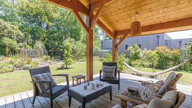 Eine Terrasse im Freien mit Korbmöbeln, einer Hängematte und einem Holzboden.