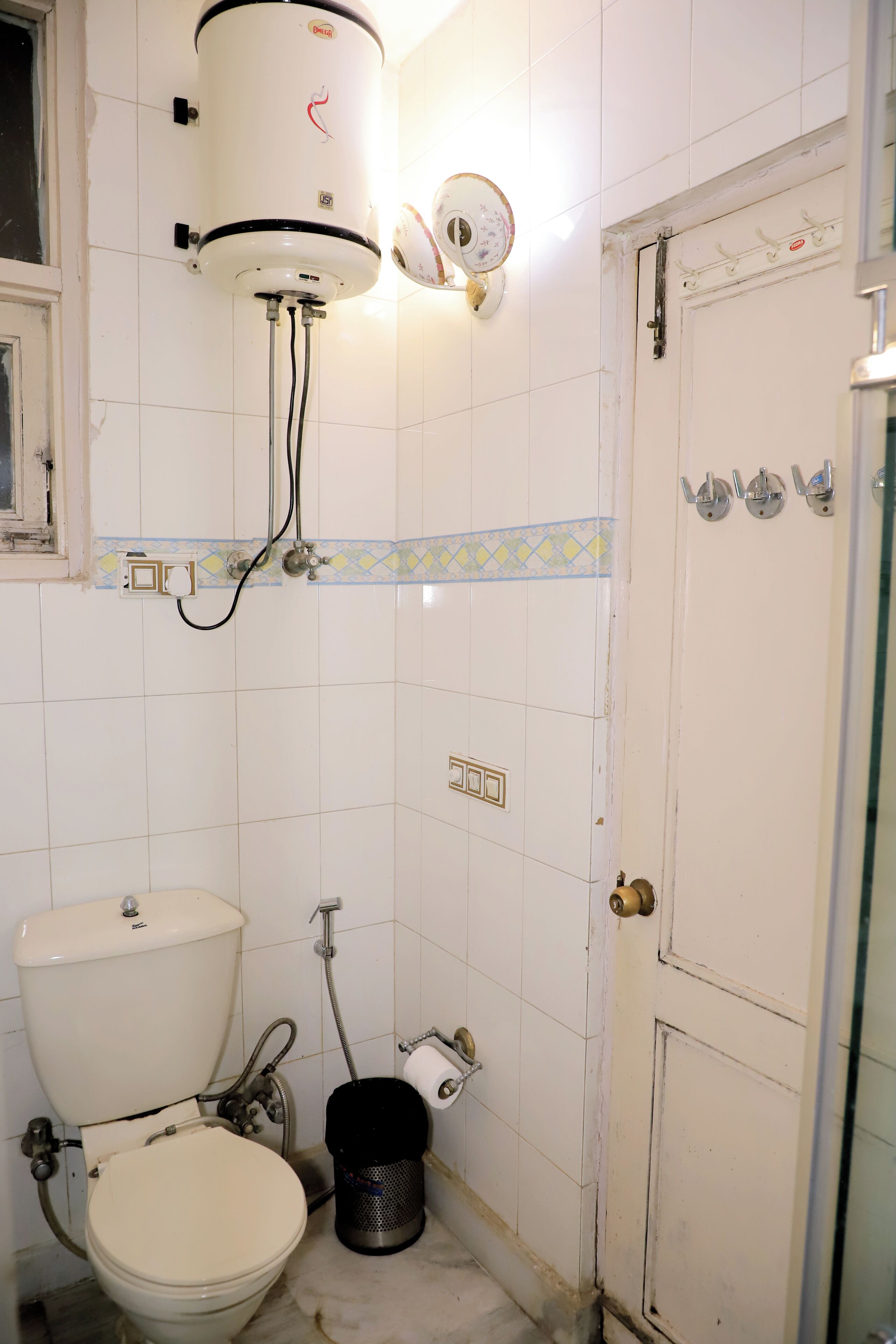 Egy fürdőszoba, amelyben WC, vízmelegítő és egy ajtó található.