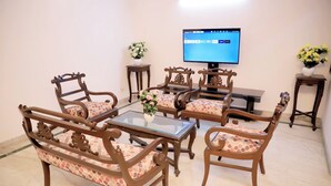 A living room with a TV, wooden furniture, and a vase with flowers. - Fortune Home Service Apartment D-198 (New Delhi)