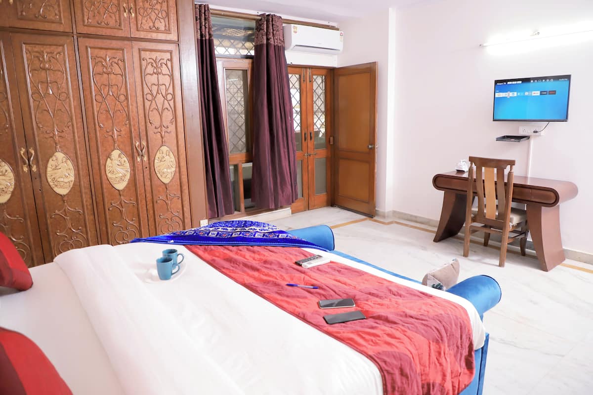 Een hotelkamer met een bed, een bureau, een stoel, een televisie en een kledingkast.