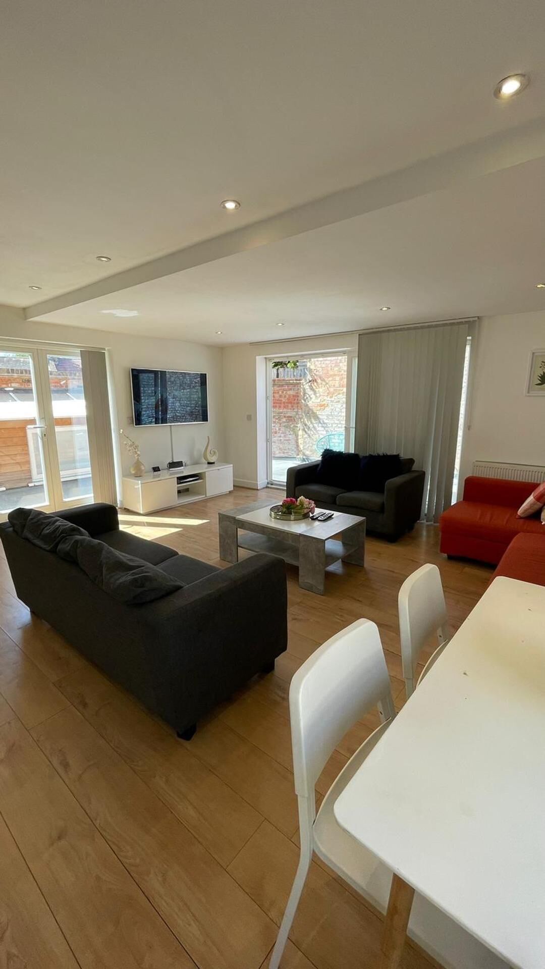 A spacious living area with a black sofa, a white coffee table, and a red sofa.