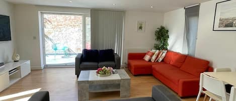 Un salon moderne avec un canapé gris, un canapé rouge, une table basse et un téléviseur.