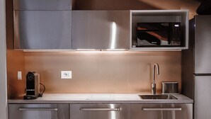 A modern kitchen with stainless steel appliances, a built-in microwave, and a sink. There are two chairs and a table with a tray of dishes. - Madama Lucrezia - Fontana di Trevi (Rome)