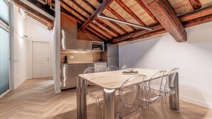 A modern kitchen with stainless steel appliances, a wooden ceiling, and a dining area with a clear table and chairs. - Madama Lucrezia - Fontana di Trevi (Rome)