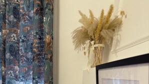 A framed sign with 'Air of Home' text, a curtain with a floral pattern, and a vase with dried flowers. - Stabia Apartment (Angri)