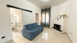 A modern living room with a blue sofa, a fireplace, and a large window with curtains. - Stabia Apartment (Angri)