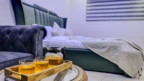 Ein Schlafzimmer mit Bett, Nachttisch mit Getränken, Sofa und Wandklimaanlage.