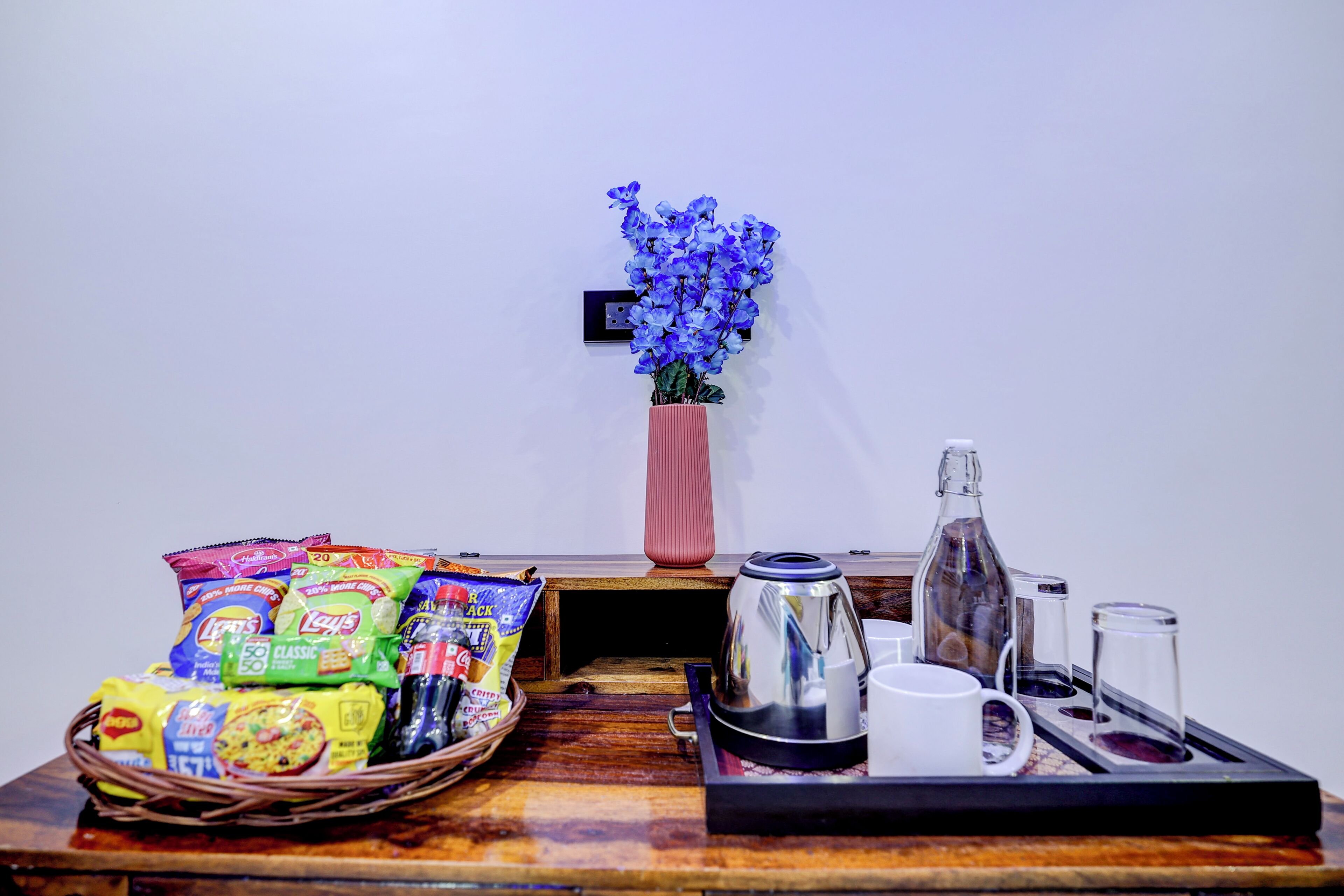 Une table en bois dressée pour le petit-déjeuner, avec des en-cas, un vase de fleurs et une cafetière.