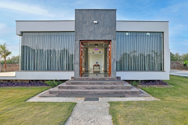 A modern building with a central entrance, large windows, and a well-maintained lawn.