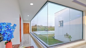Ein modernes Interieur mit Glastrennwand, Holztür und Blick auf einen Garten.