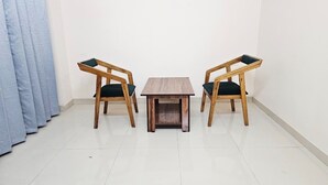 Ein Zimmer mit einem kleinen Holztisch und zwei Stühlen mit dunkel gepolsterten Sitzflächen.