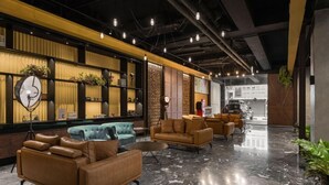 A modern lobby with leather sofas, a clock, and a plant.
