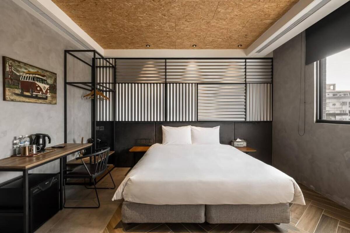 Quarto de hotel moderno com uma cama, uma escrivaninha e uma cadeira.
