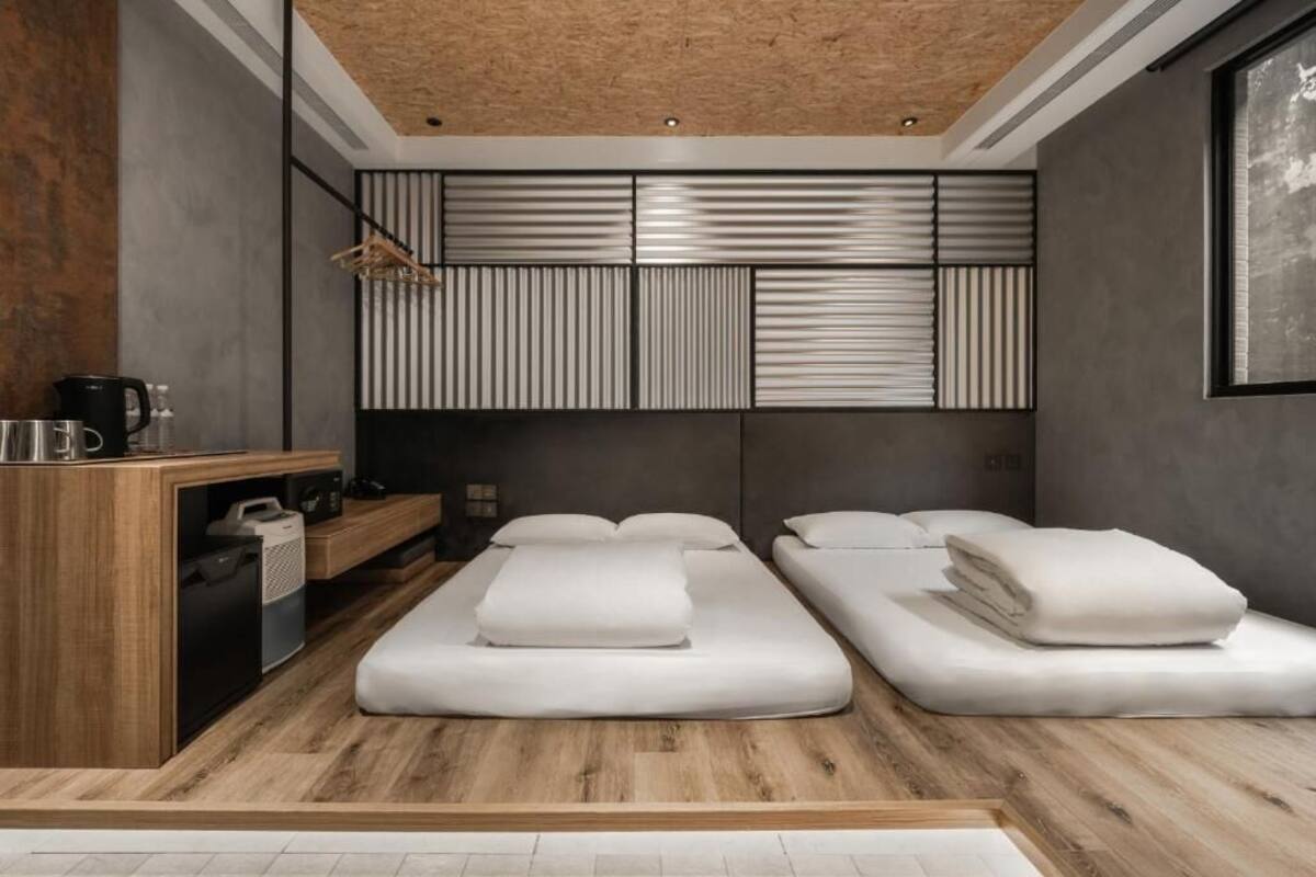 Quarto moderno com piso de madeira, mesa de massagem, pequena escrivaninha de madeira e painel fixado na parede.