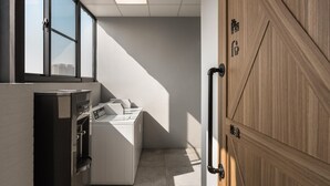 A laundry area with a washing machine and dryer, a water dispenser, and a wooden door with Chinese characters.