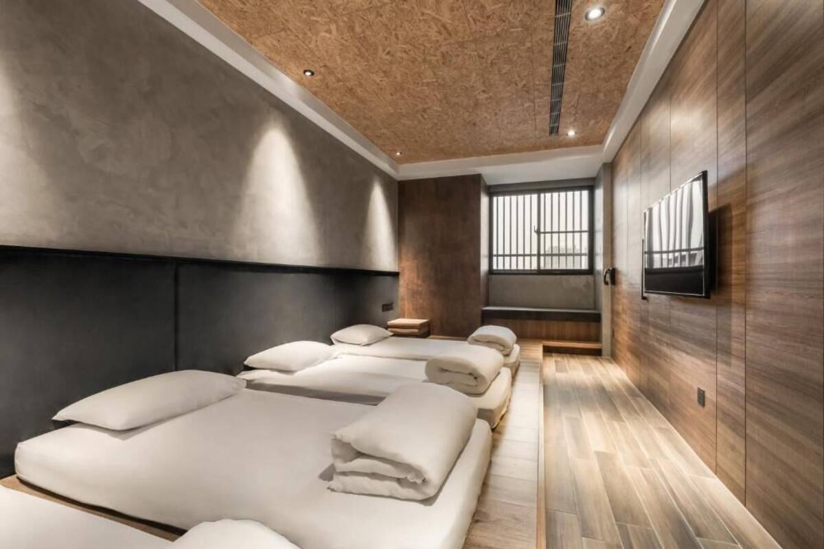Quarto de hotel moderno com uma cama grande, uma cadeira de massagem e uma TV na parede.