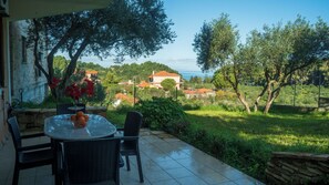 Une terrasse extérieure avec une table ronde et des chaises, entourée de verdure et offrant une vue sur des maisons et des arbres.