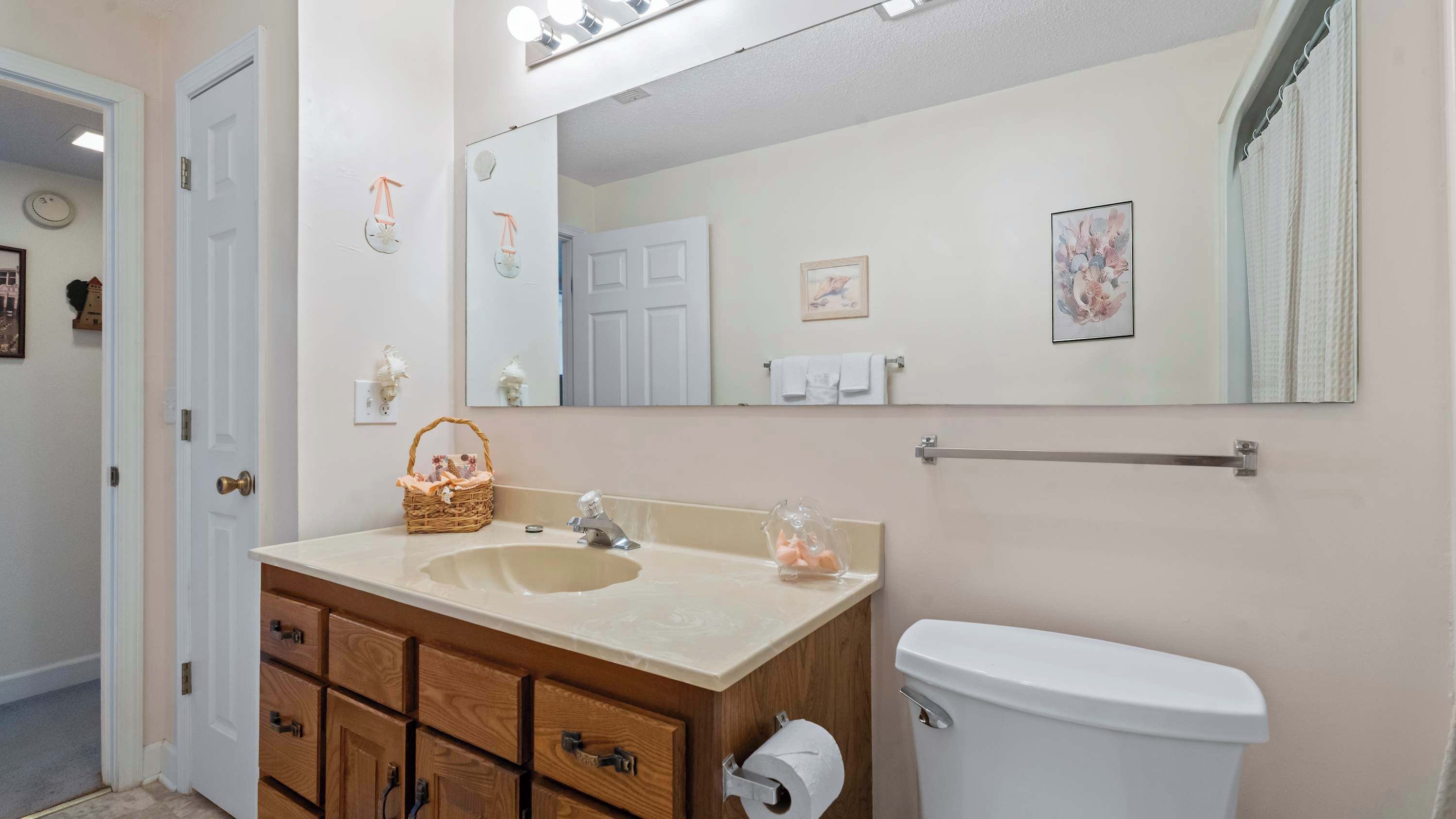 A bathroom with a sink, mirror, toilet, and wooden cabinets.