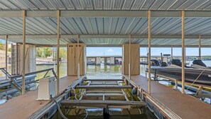 Eine überdachte Anlegestelle mit Blick auf Boote und einer Brücke im Hintergrund.