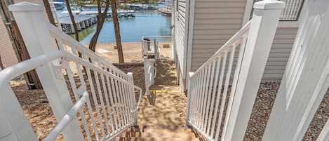 A wooden staircase leading to a dock area with a view of a lake and boats.