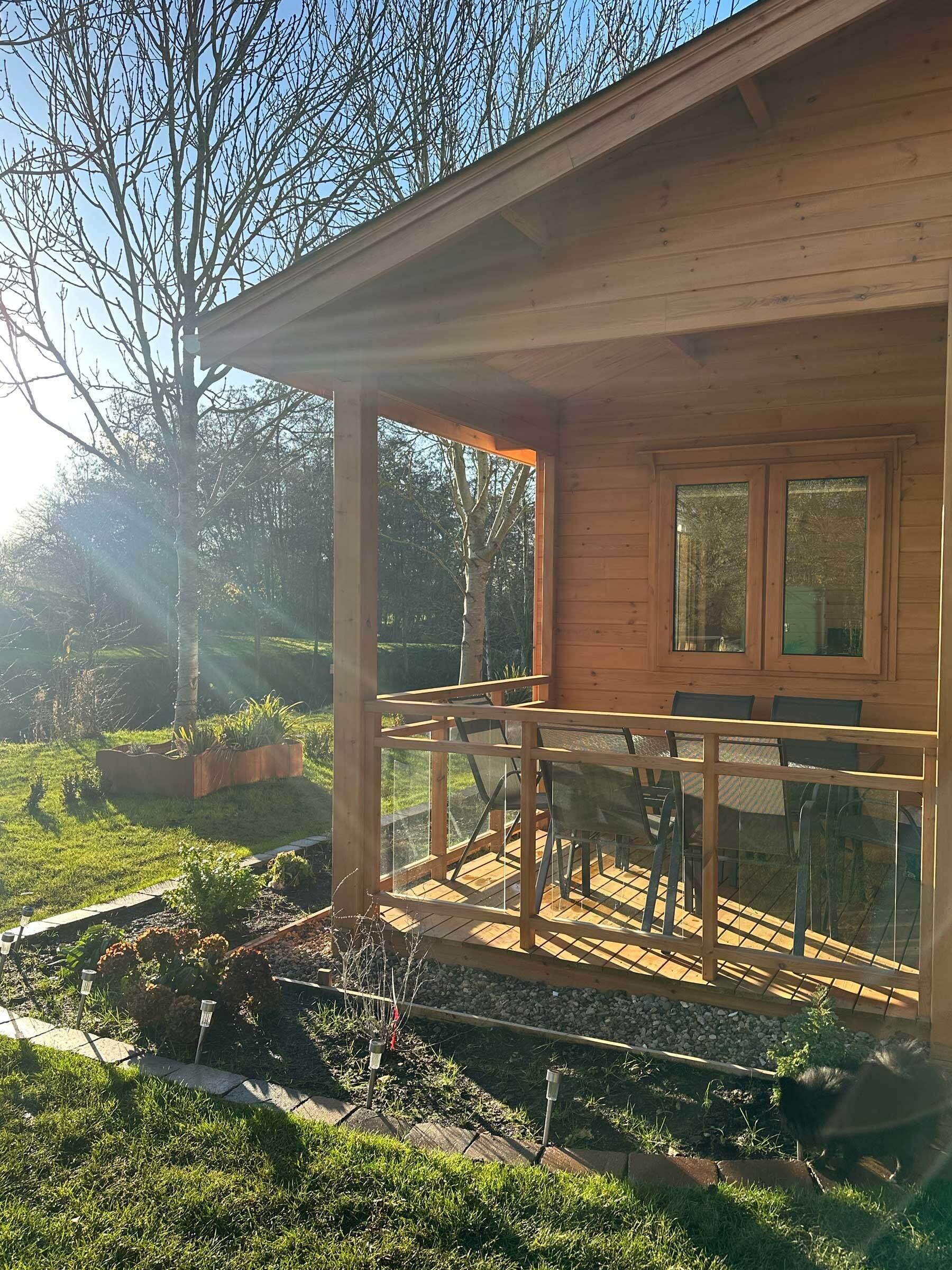 Eine Holzhütte mit Balkon, Garten und Blick auf die umliegenden Bäume.