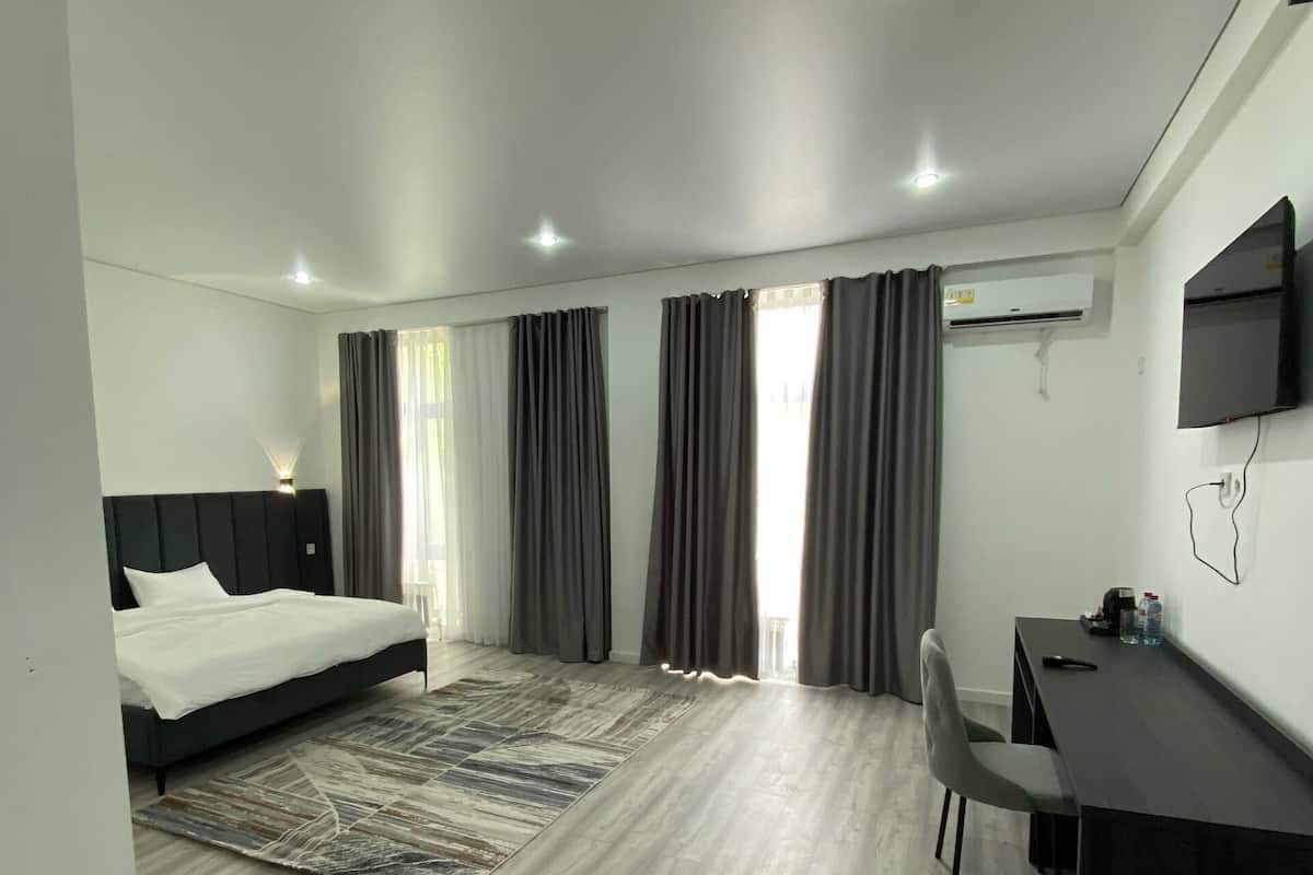 Una habitación de hotel moderna con cama, escritorio, silla y aire acondicionado.