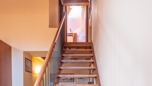 Un escalier en bois avec une rampe en métal, menant à l’étage supérieur.